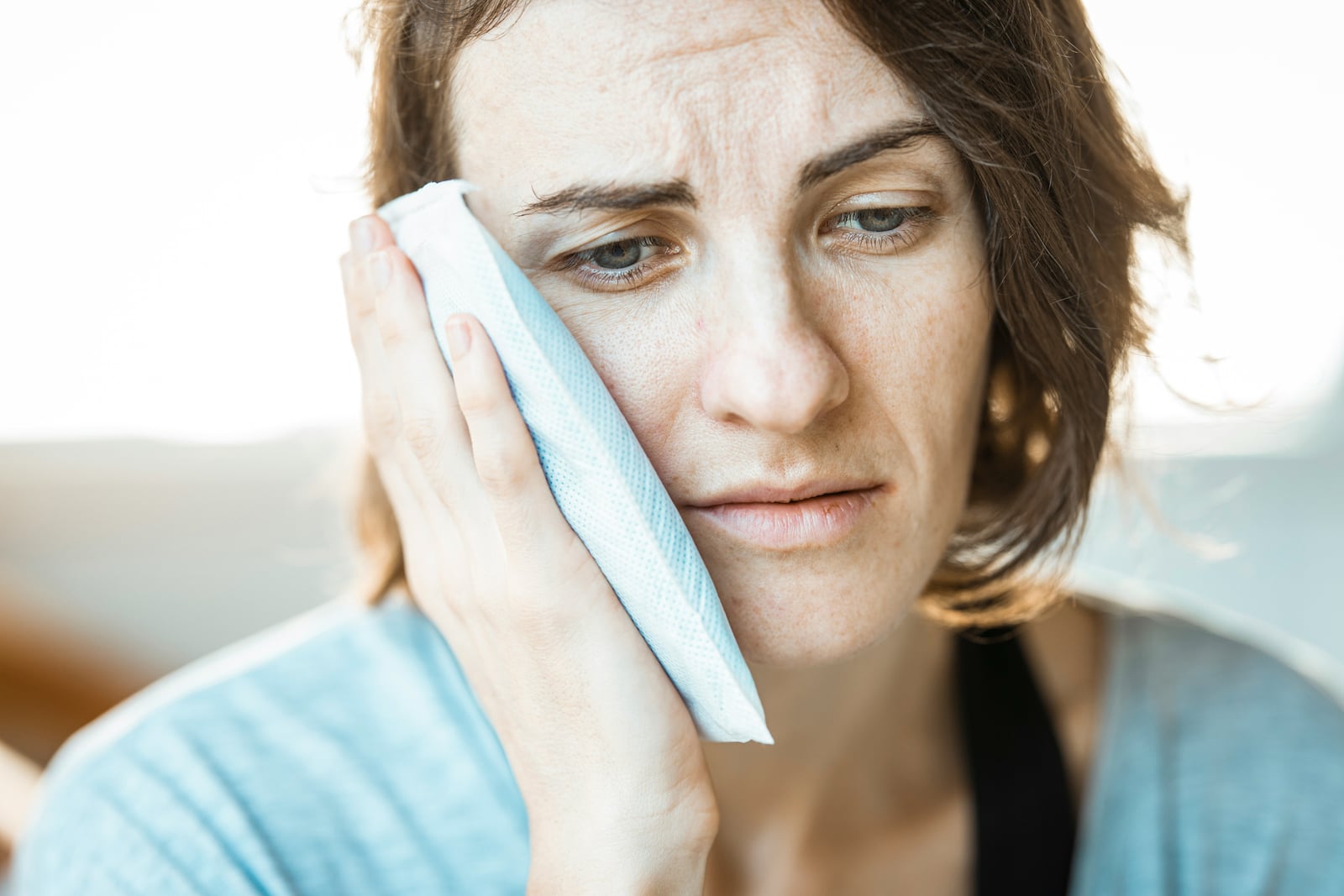 Woman pressing a cold compress against an aching jaw
